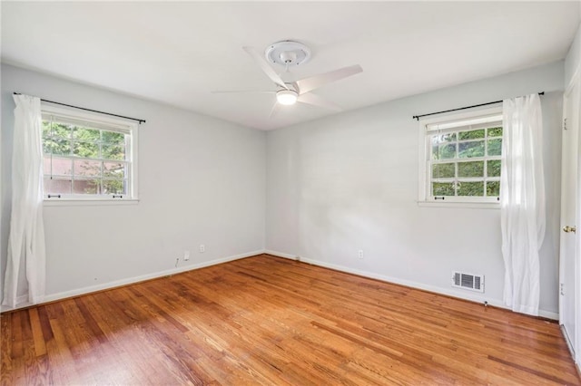 empty room featuring a ceiling fan, a healthy amount of sunlight, light wood-type flooring, and visible vents