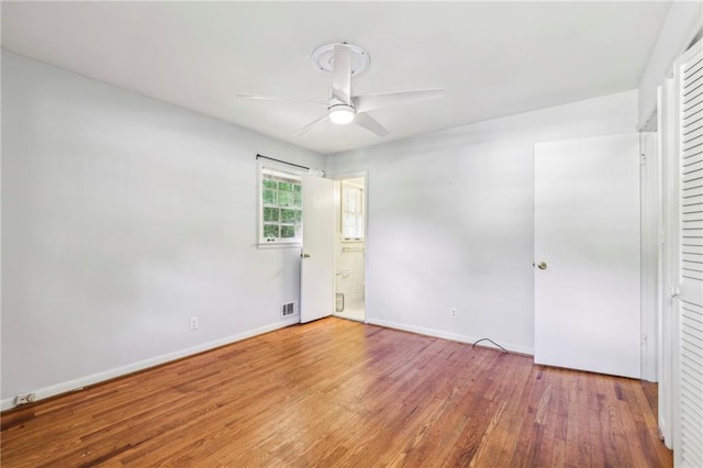 unfurnished bedroom with ensuite bath, ceiling fan, baseboards, and wood finished floors