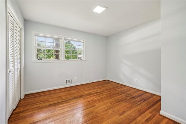 empty room with baseboards, visible vents, and wood finished floors