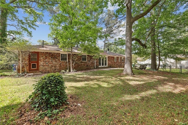 exterior space with a yard, fence, and brick siding