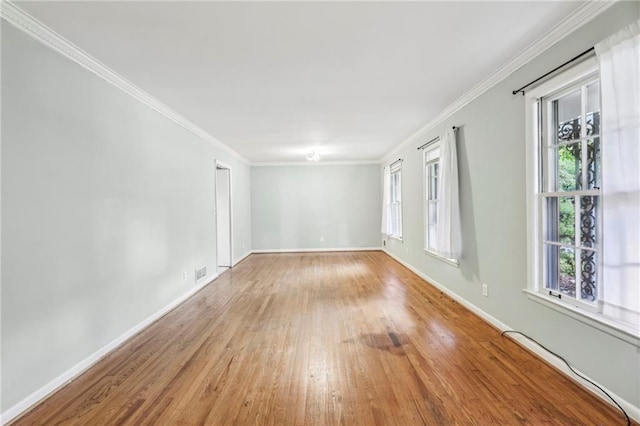 unfurnished room featuring crown molding, baseboards, plenty of natural light, and wood finished floors