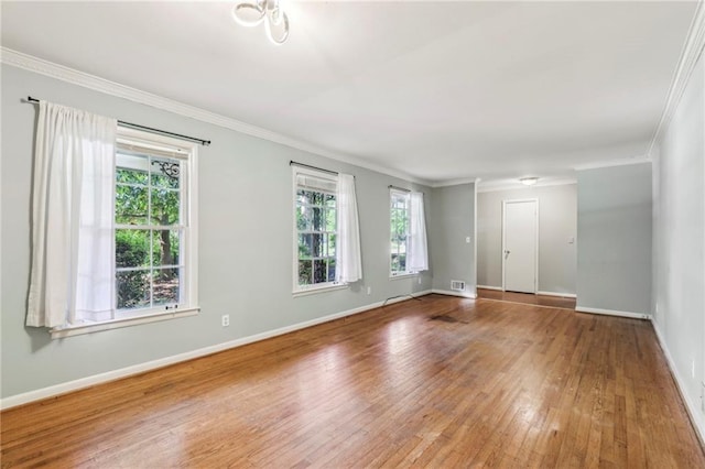 unfurnished room with visible vents, baseboards, ornamental molding, and hardwood / wood-style flooring