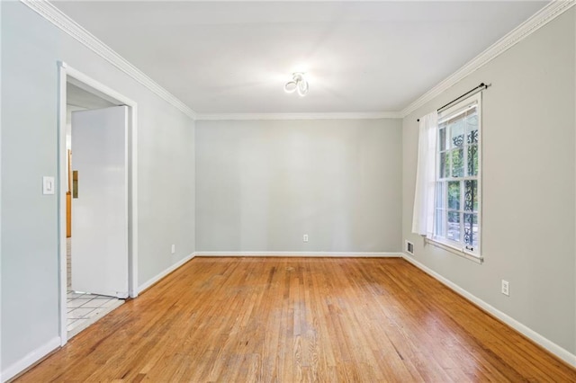 empty room with crown molding, visible vents, baseboards, and hardwood / wood-style flooring
