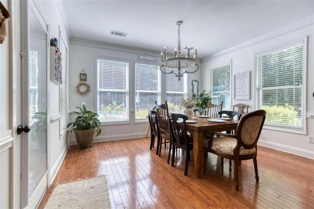 dining space with hardwood / wood-style floors, a wealth of natural light, and a notable chandelier