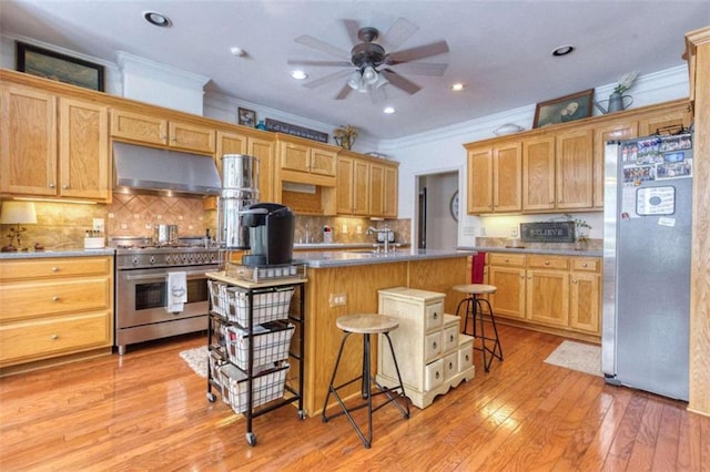 kitchen with light hardwood / wood-style flooring, a kitchen breakfast bar, ceiling fan, appliances with stainless steel finishes, and a center island with sink