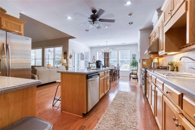 kitchen with appliances with stainless steel finishes, pendant lighting, a kitchen island with sink, and a healthy amount of sunlight