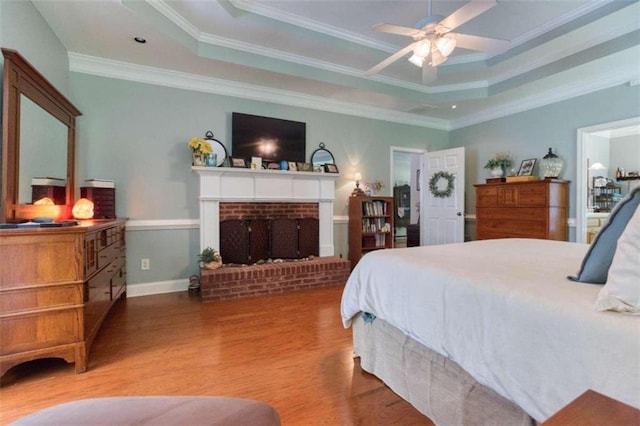 bedroom featuring ornamental molding, hardwood / wood-style floors, a tray ceiling, and ceiling fan