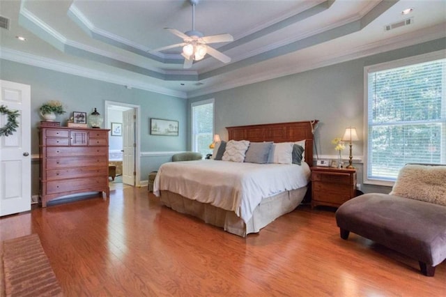 bedroom featuring a tray ceiling, ornamental molding, hardwood / wood-style floors, and ceiling fan