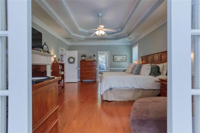 bedroom featuring hardwood / wood-style floors, ceiling fan, a raised ceiling, and ornamental molding