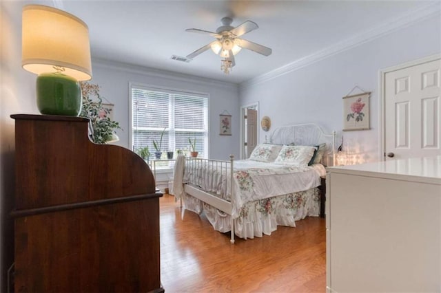 bedroom featuring ceiling fan, ornamental molding, and hardwood / wood-style flooring