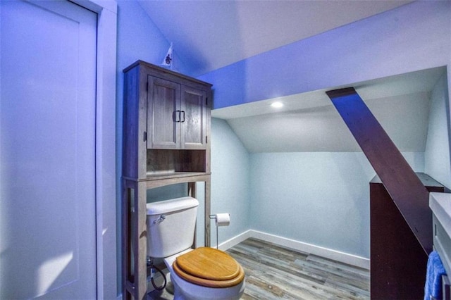 bathroom with wood-type flooring, toilet, and vaulted ceiling