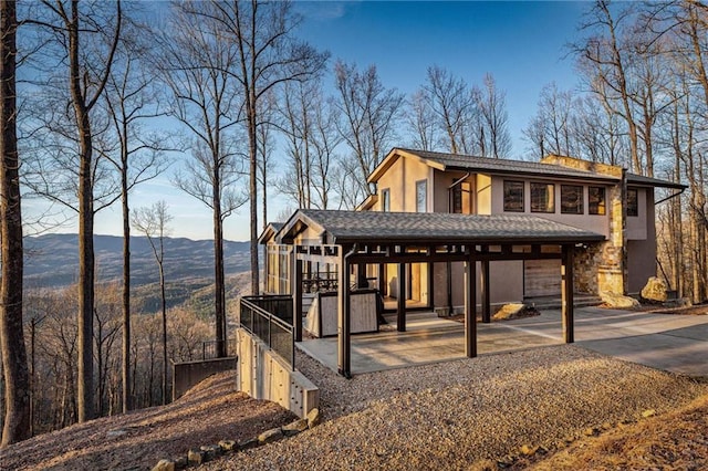 exterior space featuring stone siding, a mountain view, and stucco siding