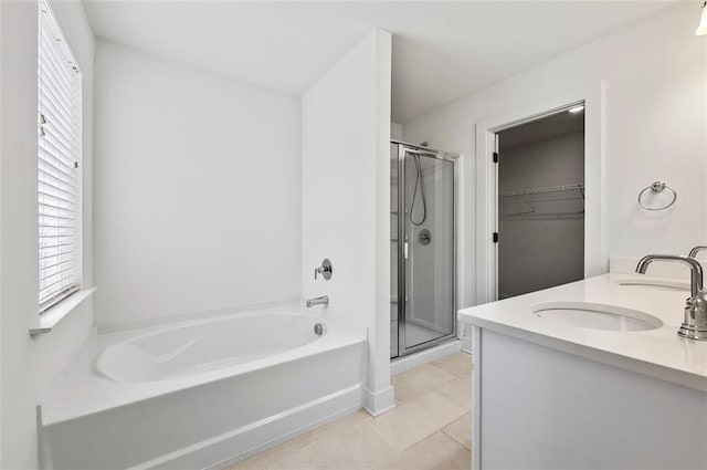 bathroom featuring a garden tub, a spacious closet, a stall shower, a sink, and tile patterned floors