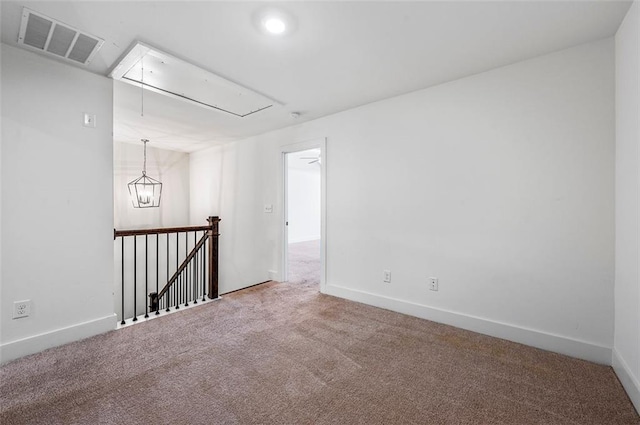 unfurnished room with visible vents, carpet floors, attic access, and baseboards