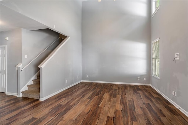 208 Oconee Way, Canton, GA 30114 - unfurnished living room with wood finished floors, stairway, baseboards, and a towering ceiling