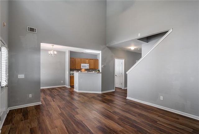 208 Oconee Way, Canton, GA 30114 - unfurnished living room with a towering ceiling, a chandelier, dark wood-style flooring, and baseboards