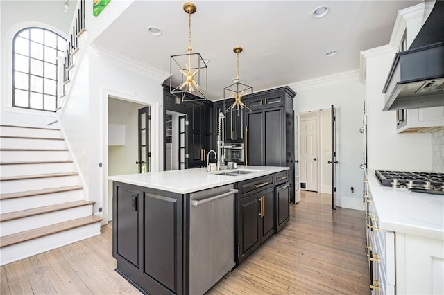 kitchen featuring light wood-type flooring, ventilation hood, stainless steel appliances, crown molding, and a center island with sink