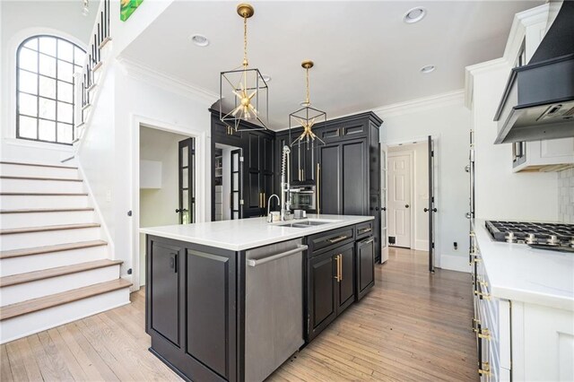 kitchen featuring sink, stainless steel double oven, an island with sink, pendant lighting, and wood-type flooring