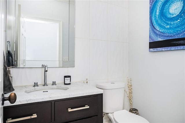 bathroom with decorative backsplash, vanity, and toilet