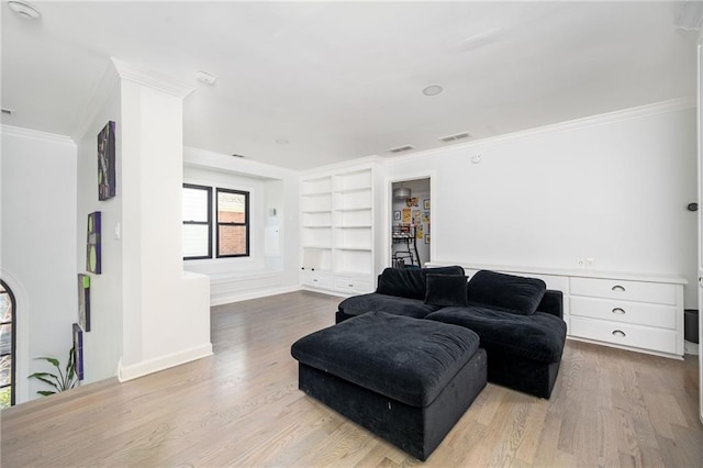 living room featuring built in shelves, light wood-type flooring, and ornamental molding