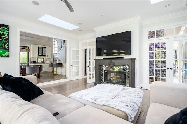 living room with ceiling fan, french doors, crown molding, a fireplace, and hardwood / wood-style flooring