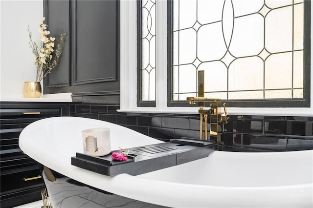 bathroom with backsplash, plenty of natural light, and a washtub