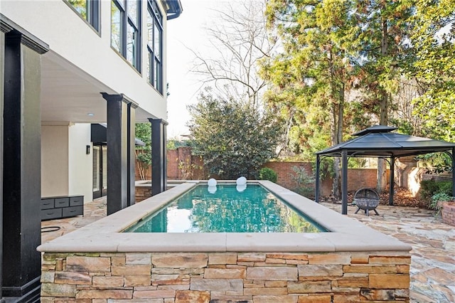 view of swimming pool with a gazebo and an outdoor fire pit