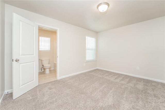 unfurnished bedroom with light colored carpet and connected bathroom