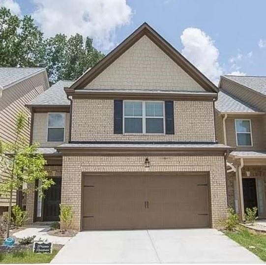 view of front of property featuring an attached garage, driveway, and brick siding