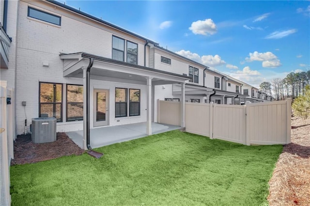 rear view of house featuring a patio, central AC, and a lawn