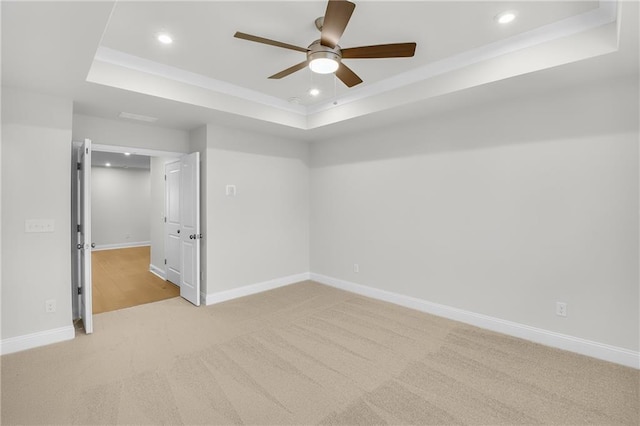 carpeted empty room with a tray ceiling and ceiling fan