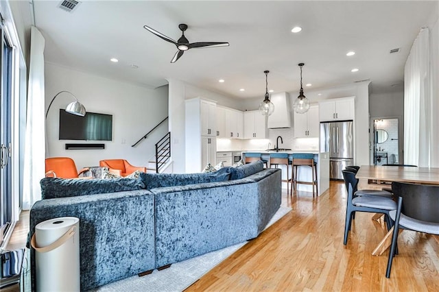 living area featuring light wood-type flooring, stairs, a ceiling fan, and recessed lighting