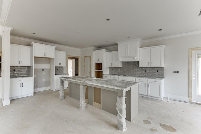 kitchen featuring white cabinets, a center island, and light stone counters