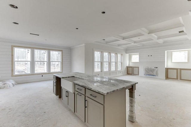 kitchen with light stone countertops, coffered ceiling, sink, beamed ceiling, and a kitchen island