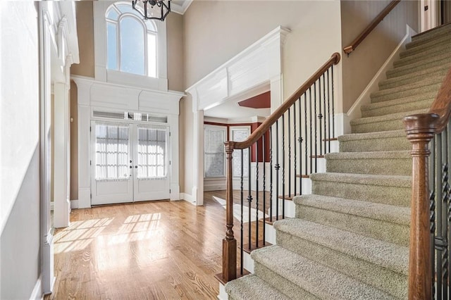 entrance foyer featuring french doors, a healthy amount of sunlight, a towering ceiling, and wood finished floors