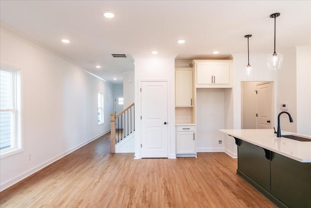 kitchen featuring light wood finished floors, a kitchen bar, visible vents, and a sink