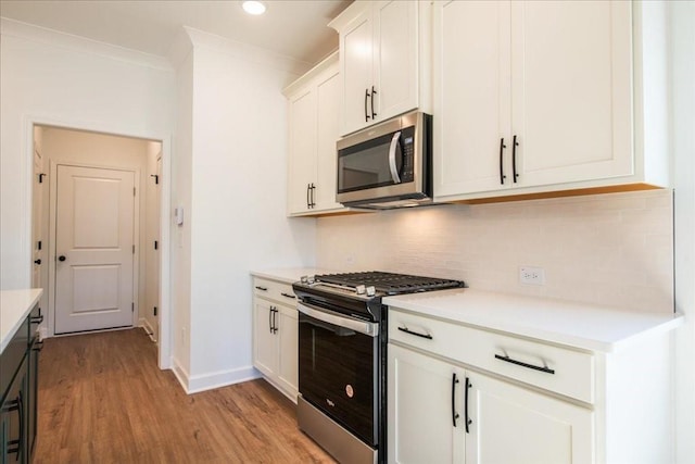 kitchen with ornamental molding, light countertops, appliances with stainless steel finishes, and backsplash