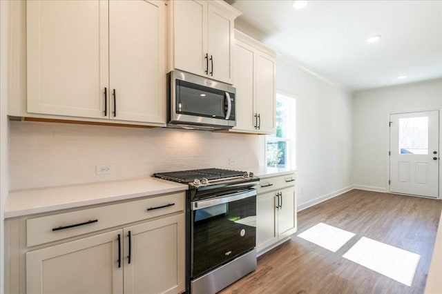 kitchen featuring stainless steel appliances, light wood-style floors, plenty of natural light, and decorative backsplash