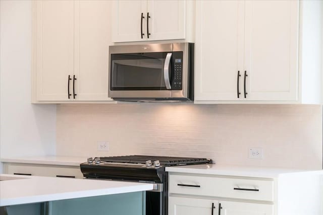 kitchen featuring white cabinetry, decorative backsplash, stainless steel appliances, and light countertops