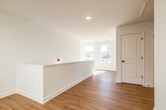 corridor with baseboards and light wood finished floors