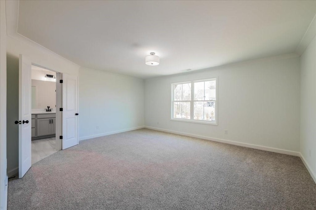 unfurnished room with light carpet, ornamental molding, a sink, and baseboards