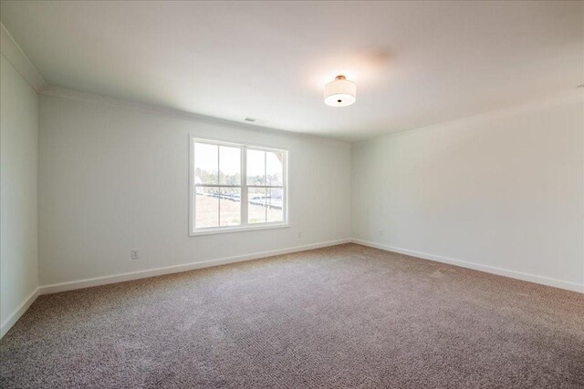 unfurnished room with visible vents, crown molding, baseboards, and carpet flooring