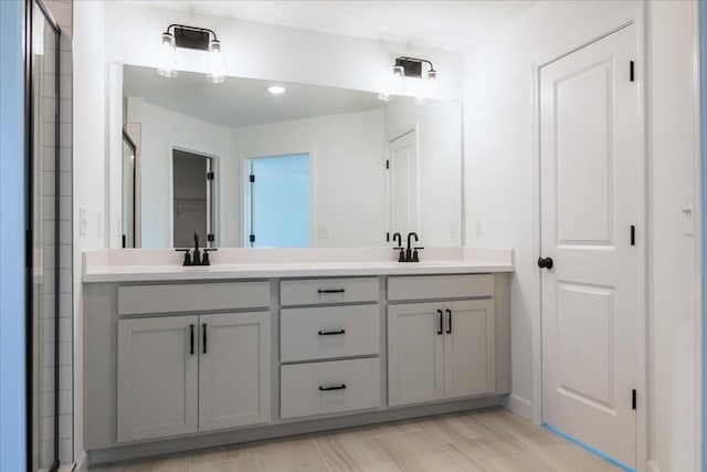 full bathroom with double vanity, a sink, and tiled shower