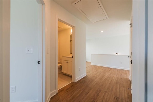 hall featuring attic access, baseboards, and wood finished floors