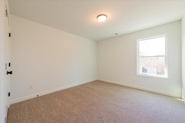 unfurnished room featuring light carpet and baseboards