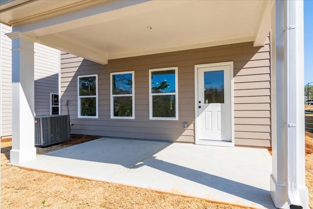 view of exterior entry featuring central air condition unit and a patio area