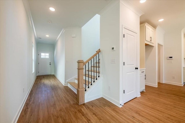 corridor featuring stairs, recessed lighting, light wood-style flooring, and baseboards