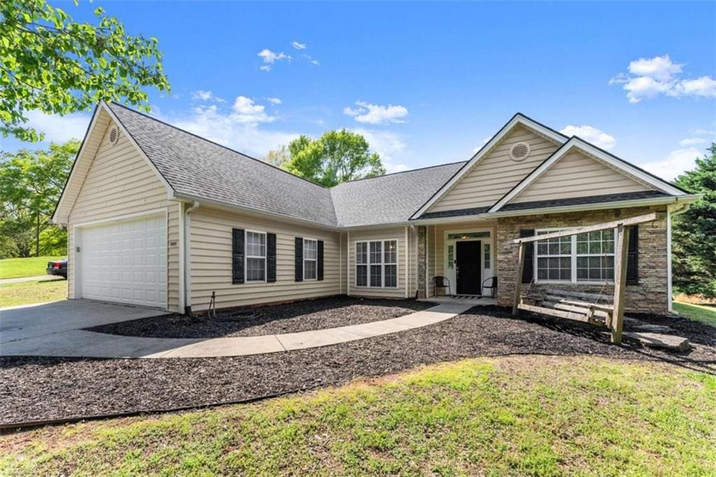 ranch-style house with an attached garage, roof with shingles, and driveway