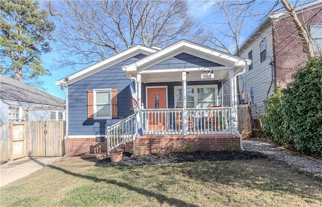 bungalow-style home with fence, a porch, and a front yard