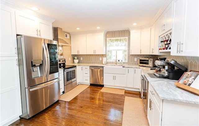 kitchen featuring tasteful backsplash, wall chimney exhaust hood, appliances with stainless steel finishes, and white cabinets